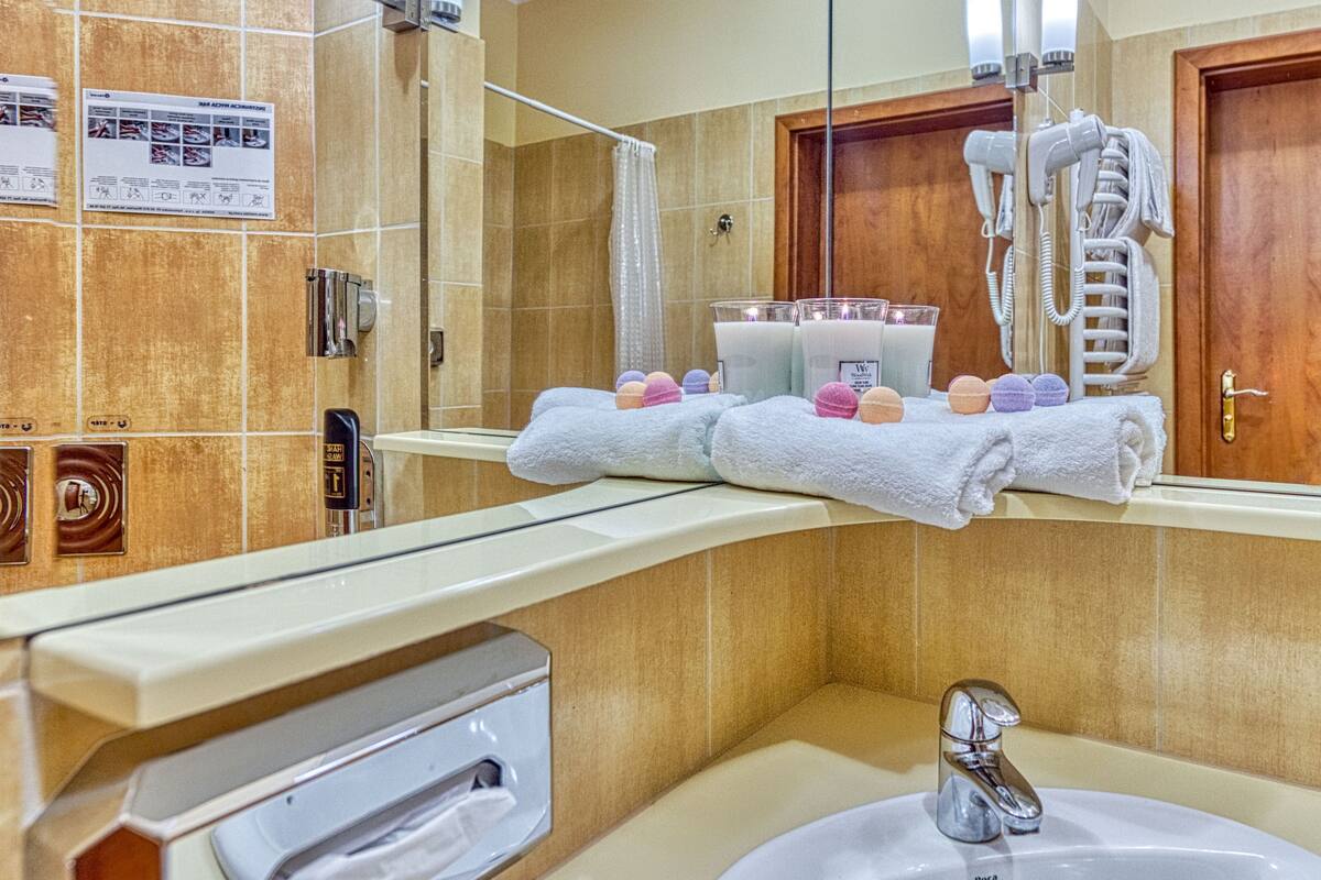 A bathroom with a sink, mirror, towel rack, and hairdryer.