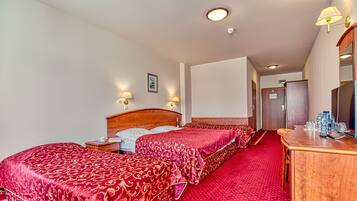 A hotel room with two beds, a wooden dresser, a mirror, and a red carpet.