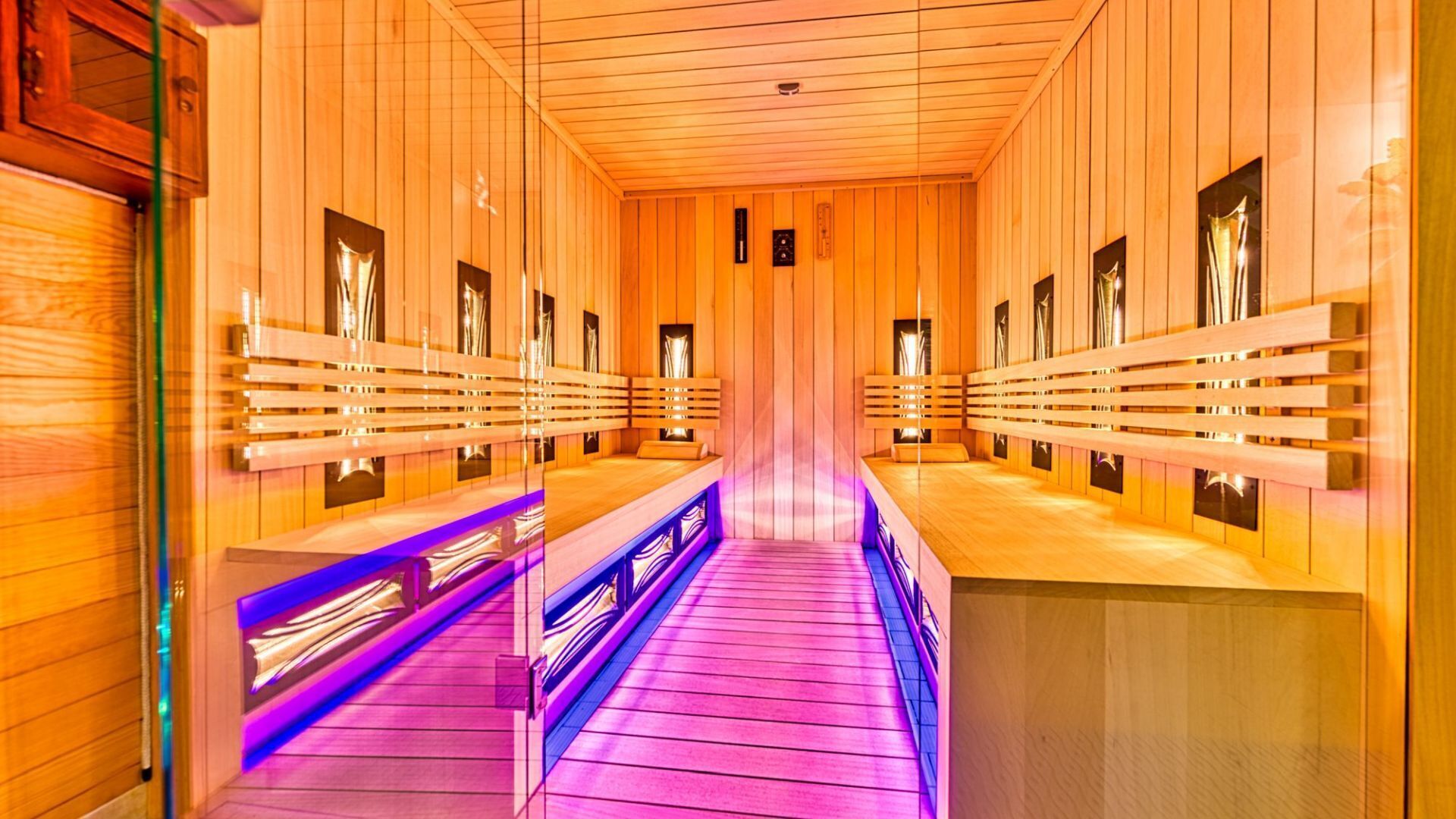 Eine Sauna mit Holzwänden und -bänken, einem zentralen Gang und einer Decke mit einer Leuchte.