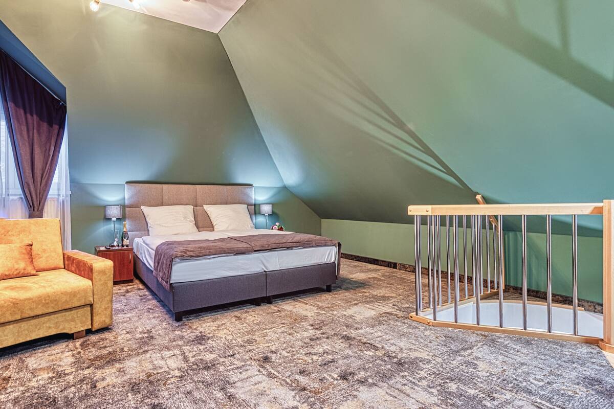 A bedroom with a bed, a sofa, a nightstand, and a crib.