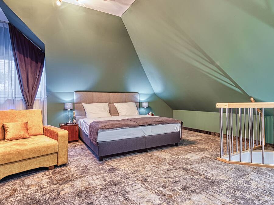A bedroom with a bed, a sofa, a nightstand, and a crib.