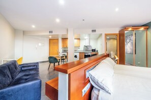 Ein Hotelzimmer mit Bett, Schreibtisch, Stuhl und einer Küchenzeile.