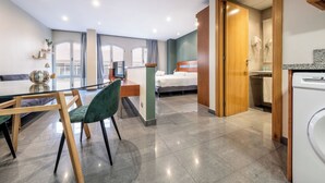 Una habitación de hotel moderna con comedor, cama y kitchenette.