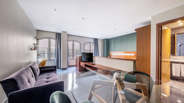 Una sala de estar moderna con una mesa de centro de vidrio, un sofá y una televisión.