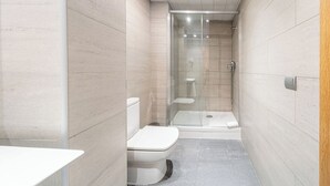 Un baño pequeño con inodoro, ducha con puerta de cristal y lavabo.