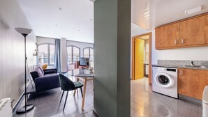 Un apartamento moderno con sala de estar, comedor y cocina equipada con lavadora.