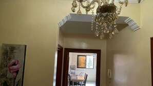 Ein Korridor mit einer Chandelier, ein Essbereich mit Tisch und Stühlen sowie ein Gemälde an der Wand.