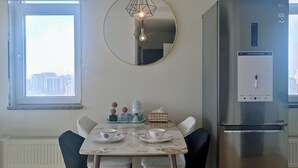 Une cuisine moderne avec un miroir rond, un réfrigérateur en acier inoxydable et une table à manger avec des chaises.