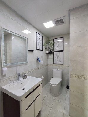 Un bagno con lavandino, specchio, WC e opere d'arte appese alle pareti.