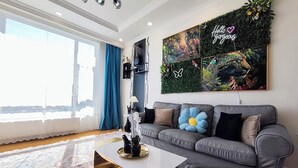 Un salon moderne avec un canapé gris, une table basse et une grande fenêtre avec des rideaux.