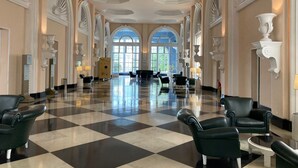 Un hall d’entrée spacieux, doté d’un sol à carreaux, d’élégants fauteuils en cuir noir et de décorations murales blanches raffinées.