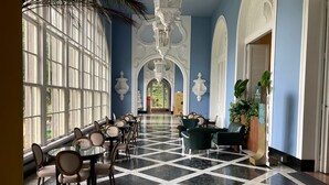 Un hall d’hôtel avec un sol à carreaux, de grandes fenêtres et un espace salon central.