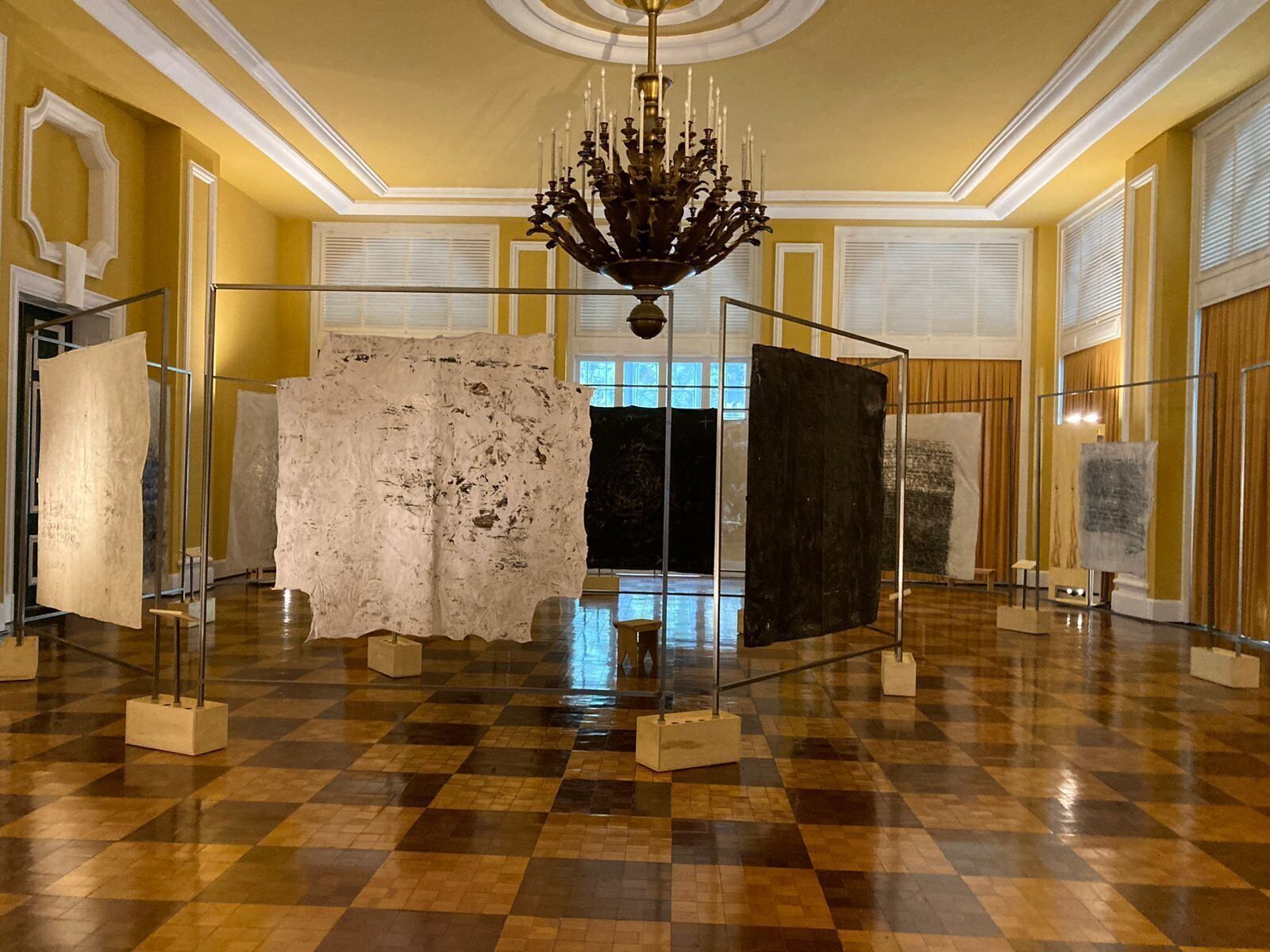 Taidegalleria, jossa on esillä suuria veistoksia, koristeellinen kattokruunu ja ruutukuviollinen lattia.