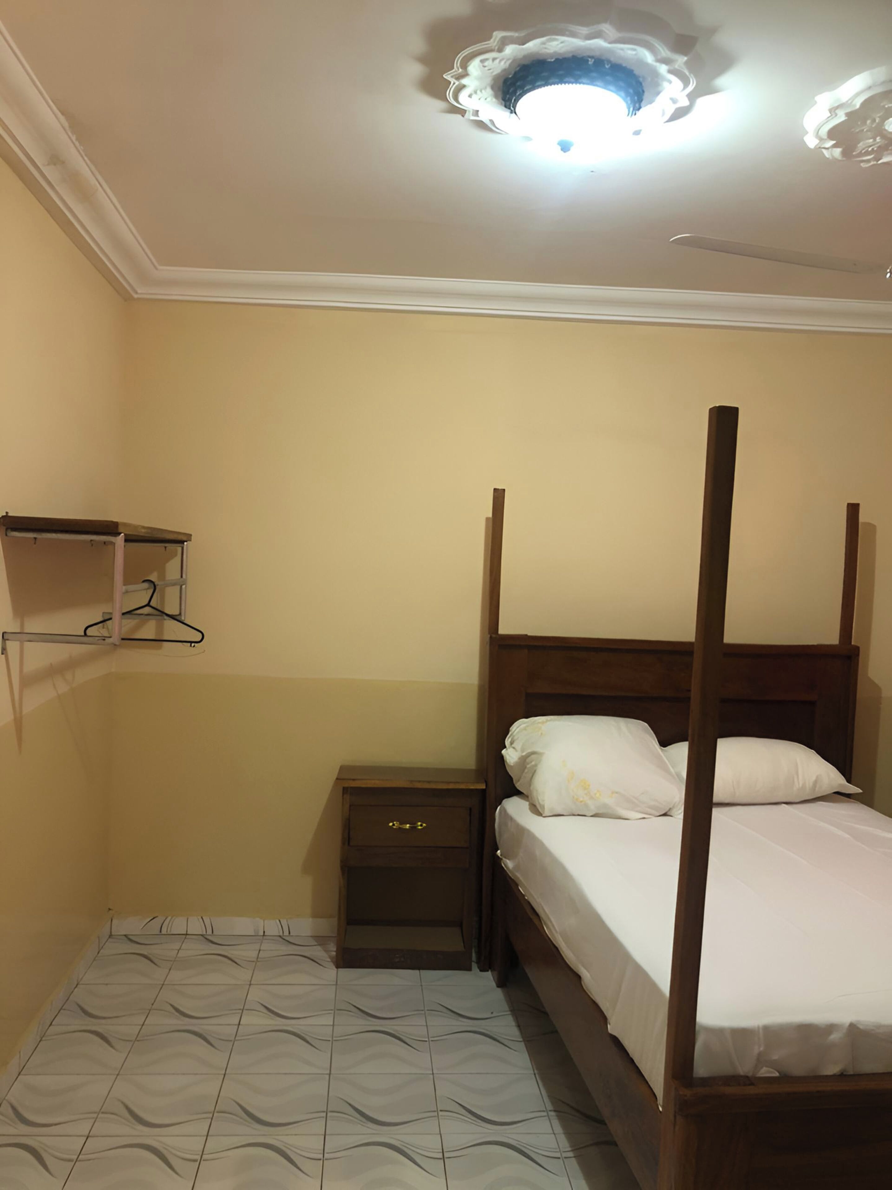 Una camera da letto con un letto a baldacchino, un comodino, una mensola a parete e un pavimento decorato.