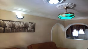 A living room with a ceiling fan, a wall-mounted light, and a floral painting.