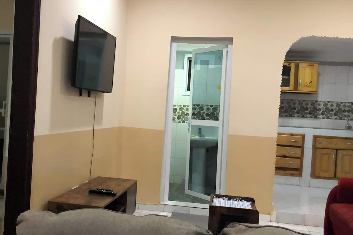 Un salon avec un téléviseur fixé au mur, une petite table en bois et un canapé.
