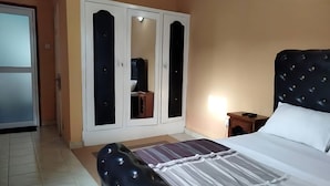 A bedroom with a bed, a wardrobe, and a nightstand.