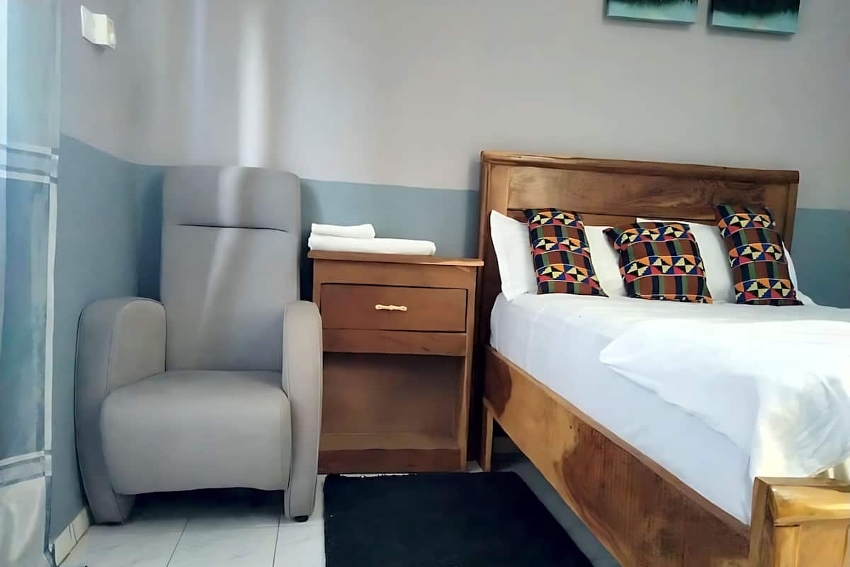Une chambre à coucher comprenant un lit, une chaise, une table de chevet et une tête de lit en bois.