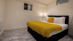 Quarto com uma cama, abajur, janela e um quadro na parede.