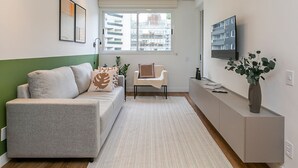 A modern living room with a sofa, a chair, a TV, and a plant. - WI-FI 180MB | 200m from Beiramar Shopping #CA52 (Florianópolis)