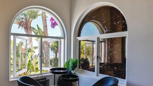 A room with two large arched windows, a round table, and two black chairs.