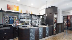 A modern bar area with a curved counter, stainless steel appliances, and a glass display case.