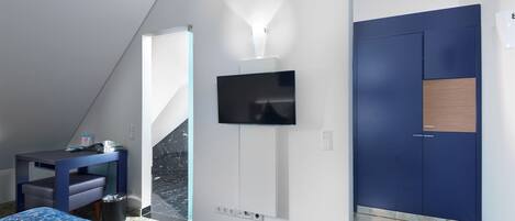 Una camera d'albergo moderna con un letto, una scrivania, una televisione a parete e un armadio.