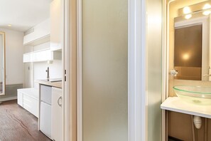 A modern bathroom with a glass sink, a mirror with lights, and a white vanity. - GuestReady - Parisian Life near Bastille Plaza (Paris)