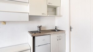 Eine kompakte Küchenzeile mit eingebautem Herd, Spüle und kleinem Kühlschrank.
