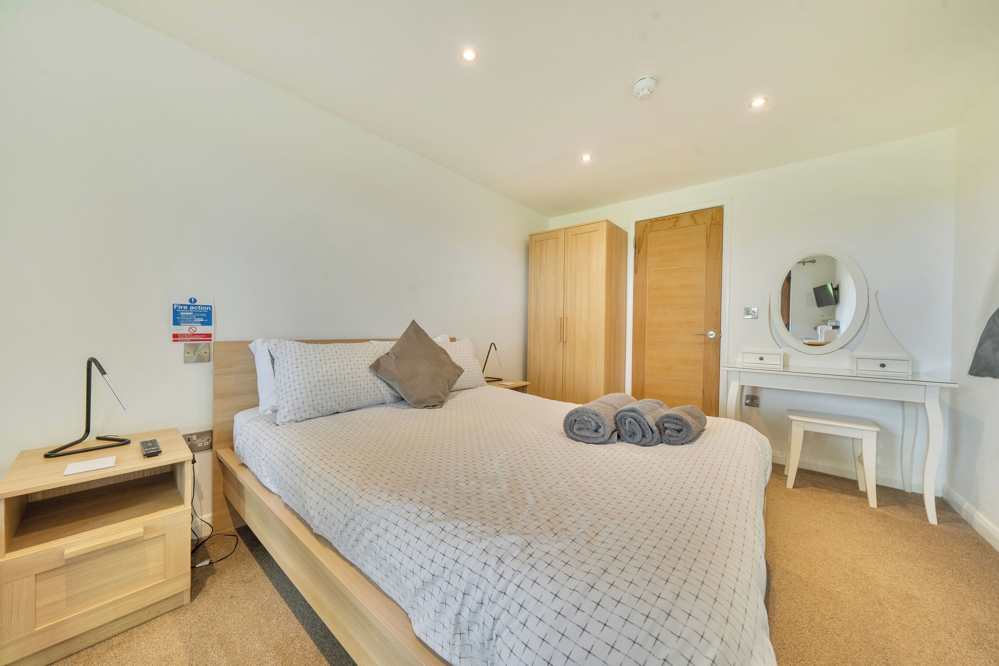 A bedroom with a bed, bedside table, lamp, and a wardrobe.