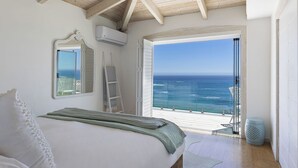Un dormitorio con una cama grande, vista al océano y un balcón con barandilla.