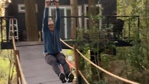 A person on a rope swing bridge in a wooded area. - Yeti's Tree House: Where Magic Happens (Portland)