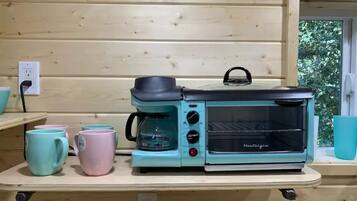 A kitchenette with a coffee maker, toaster oven, and two mugs on a wooden countertop.