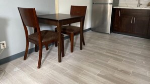 A kitchen with a wooden table and chairs, a stainless steel refrigerator, and dark wooden cabinets. - Backyard Escape

 (Tampa)