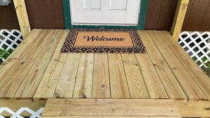 A wooden deck with a welcome mat in front of a white door. - Backyard Escape

 (Tampa)
