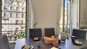 A dining table with plates of food, a basket of bread, and a coffee pot.