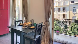 Un balcon avec une table à manger, des chaises et un pot de fleurs.