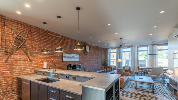 Une cuisine moderne avec un mur en briques, des luminaires suspendus et un grand îlot central.