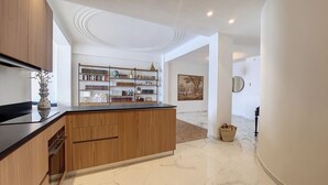 A modern kitchen with wooden cabinets, a marble countertop, and a built-in bookshelf.