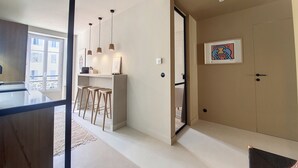 A modern kitchen with a bar area, pendant lights, and a framed artwork on the wall.