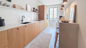A modern kitchen with wooden cabinets, a white countertop, and a built-in oven. There is a window with a view of the city.
