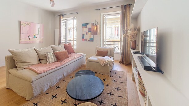 A living room with a sofa, a coffee table, a TV, and artwork on the walls.