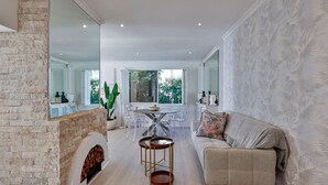 A spacious living area with a fireplace, a dining table with chairs, a sofa, and a large mirror reflecting the room.
