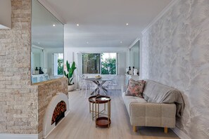 Un amplio salón con chimenea, una mesa de comedor con sillas, un sofá y un espejo grande.