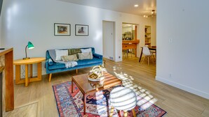 Un salon avec un canapé bleu, une table basse en bois et un tapis à motifs.
