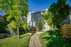 A house with a stone pathway leading to a green door, surrounded by lush greenery and a wooden fence. - Nifty Salt Lake City Apt: 2 Mi to Downtown! (Salt Lake City)