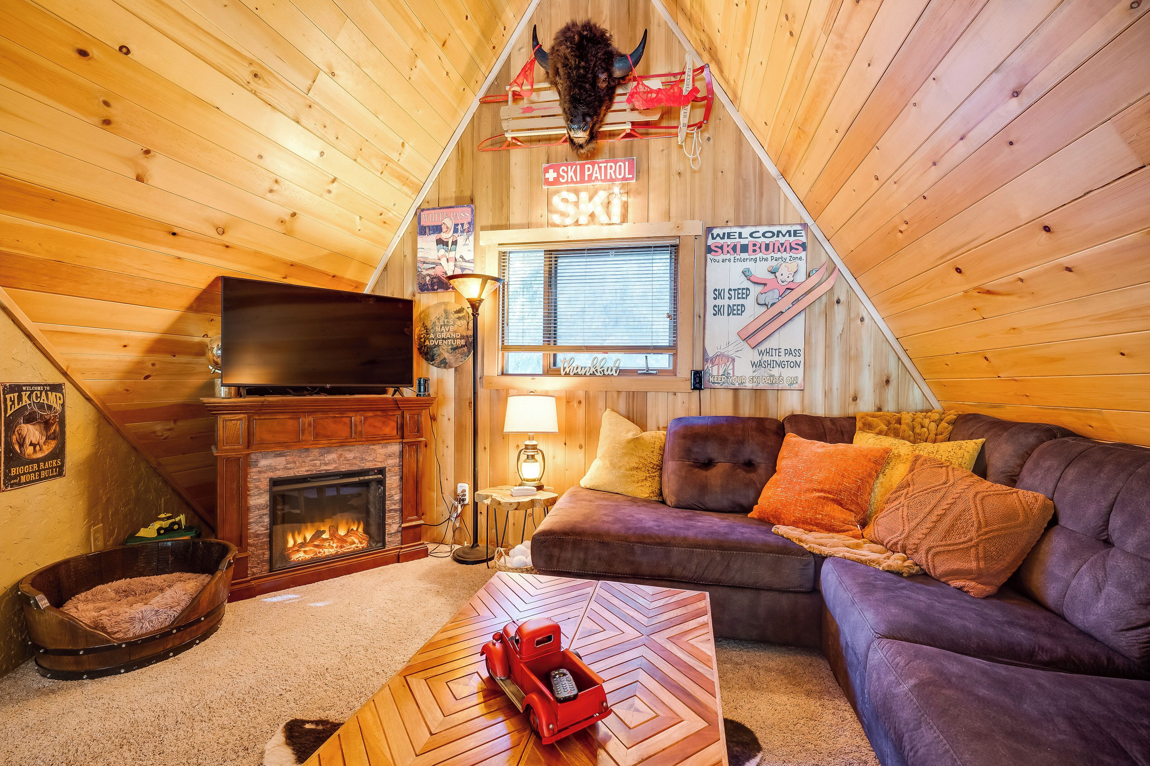 A cozy cabin interior with a fireplace, a couch, a television, and a sign indicating a ski patrol area.