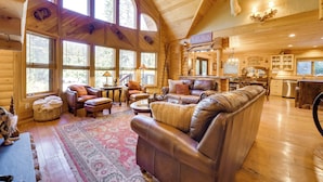 A log cabin interior with a large leather sofa, a dining table, and a kitchen area. - Spacious Packwood Cabin w/ Hot Tub - Near River (Packwood)