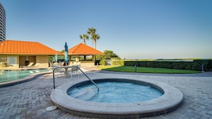 Tinaja circular con piscina al fondo, rodeada por un patio de ladrillo y sillas de descanso.