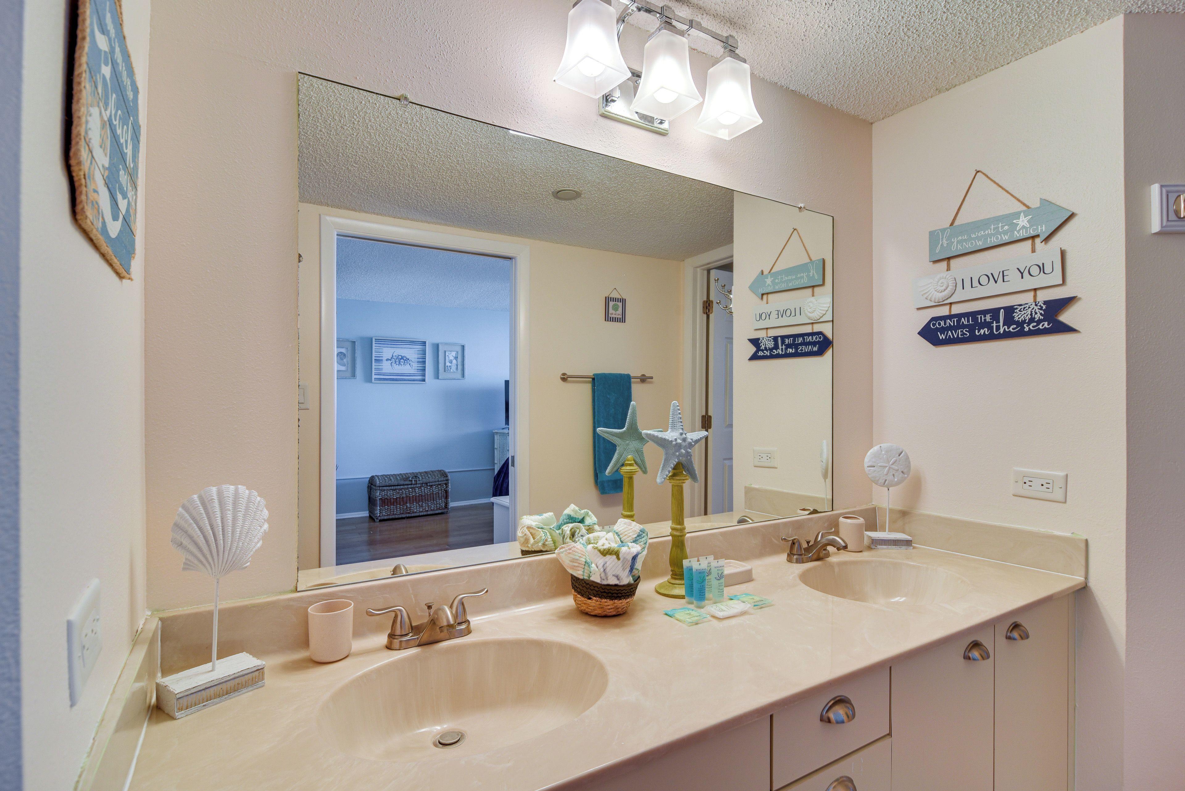 A bathroom with two sinks, a large mirror, and decorative wall signs.